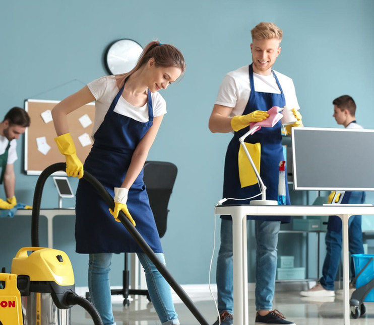 Professional cleaning crew works in office, CAUTION sign, vacuuming, dusting.